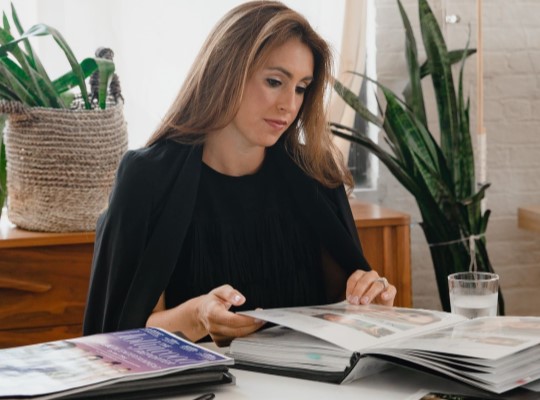 Mulher em uma mesa organizando portfólio de trabalhos.